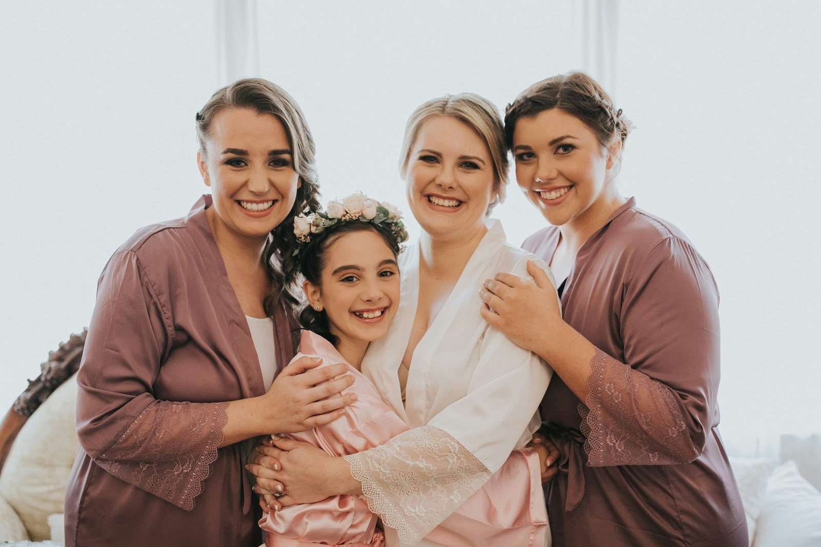 Bride, bridesmaid and flower girl hugging. Getting ready for wedding in their dressing gowns.