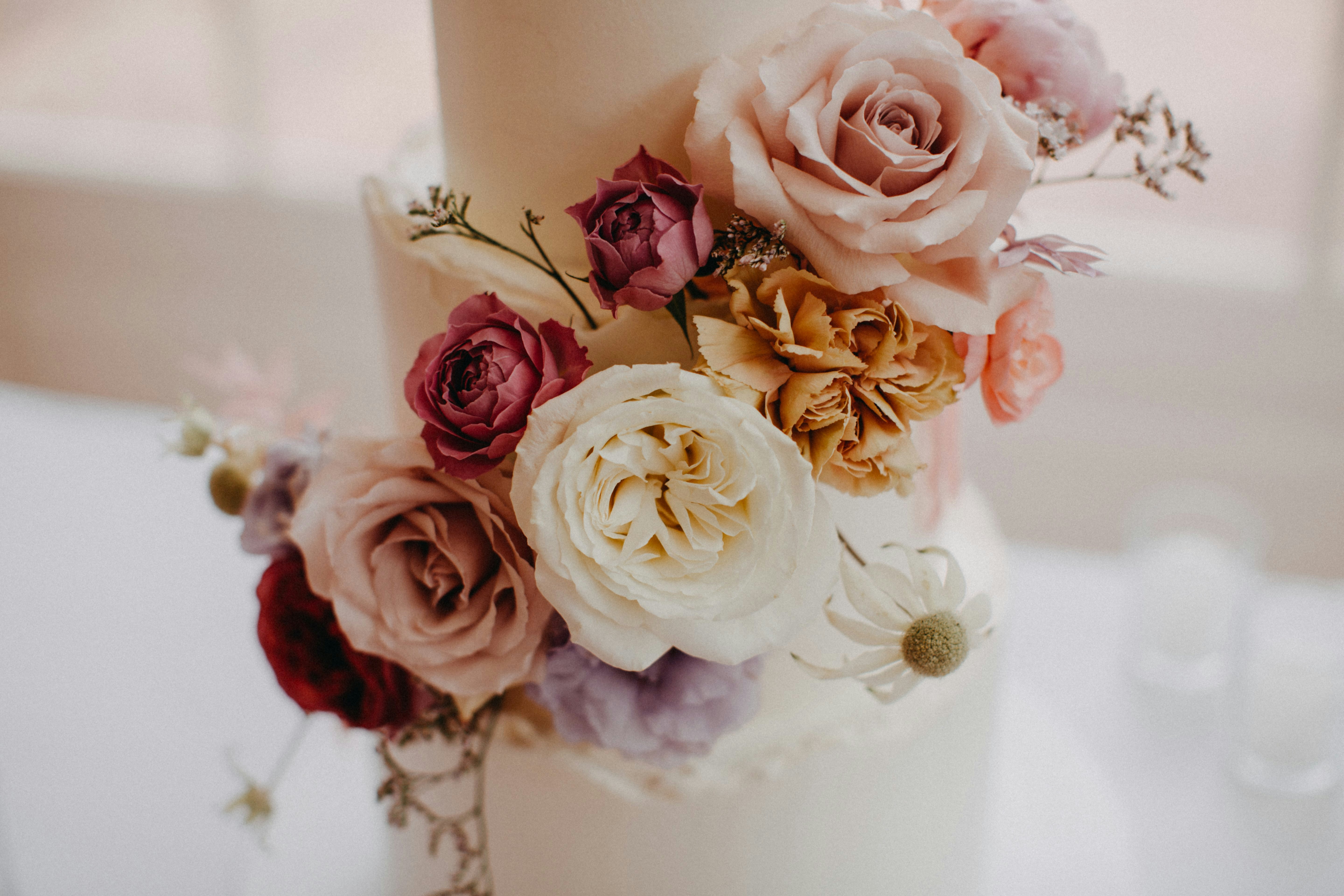 Three tiered wedding cake covered in pastel floral blooms 
