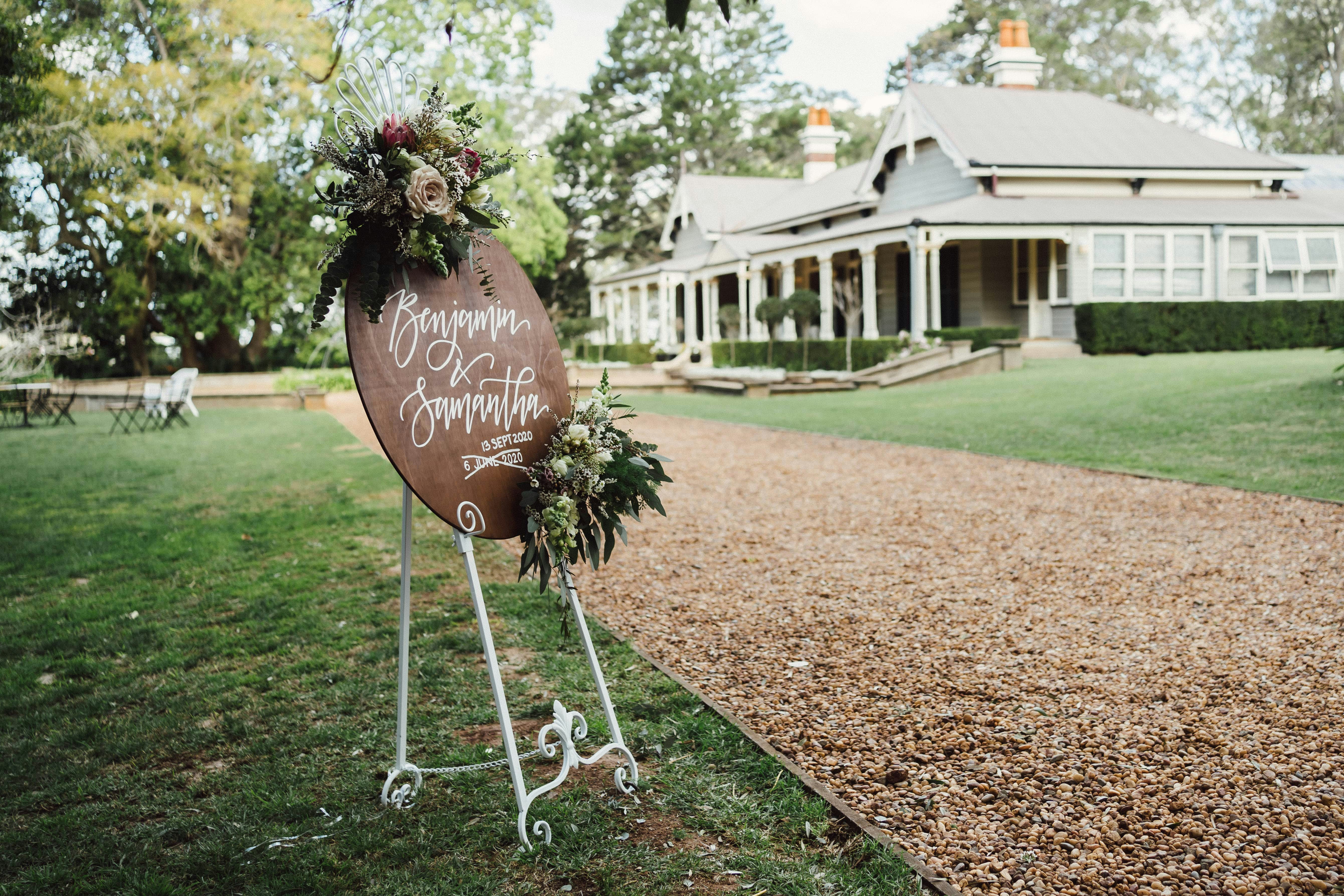 Circular wooden welcome sign on lawn at wedding venue 