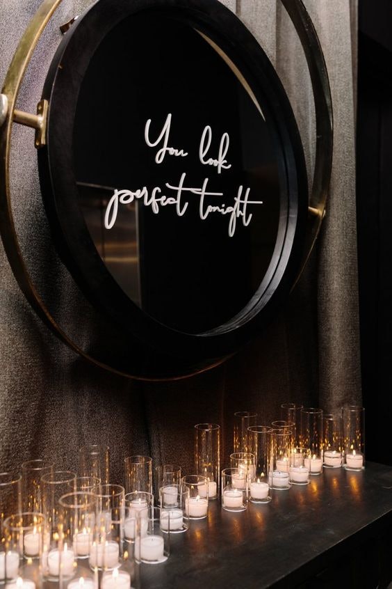 A large mirror that has 'you look perfect tonight' written on it with pillar candles underneath it. 