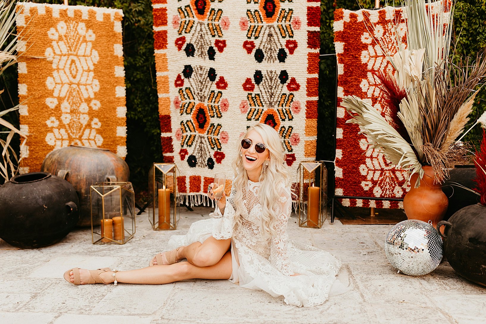 Bride sitting in front of colourful tapestry rug arbor 