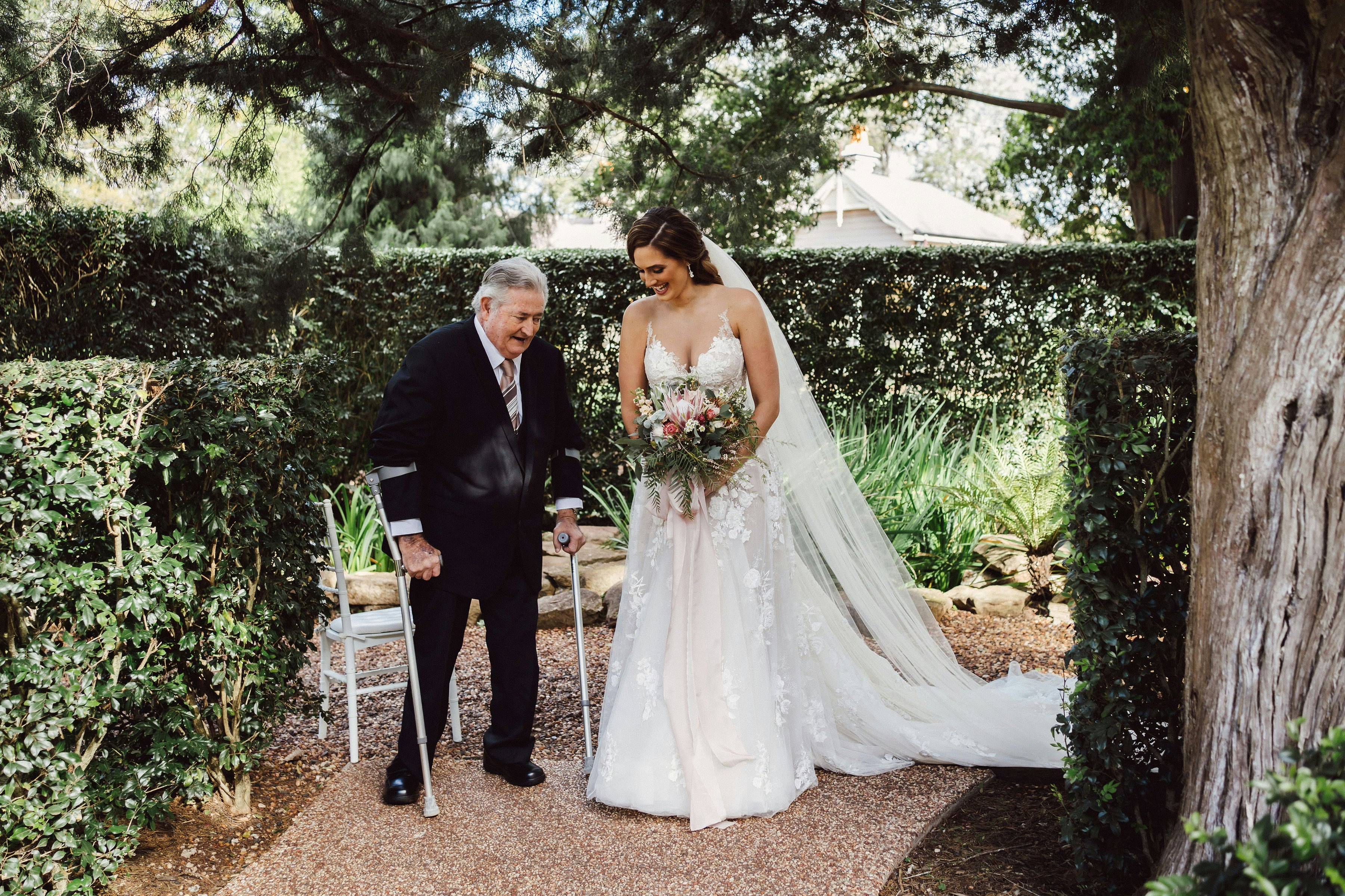 Bride meeting her father with crutches to walk down the aisle 
