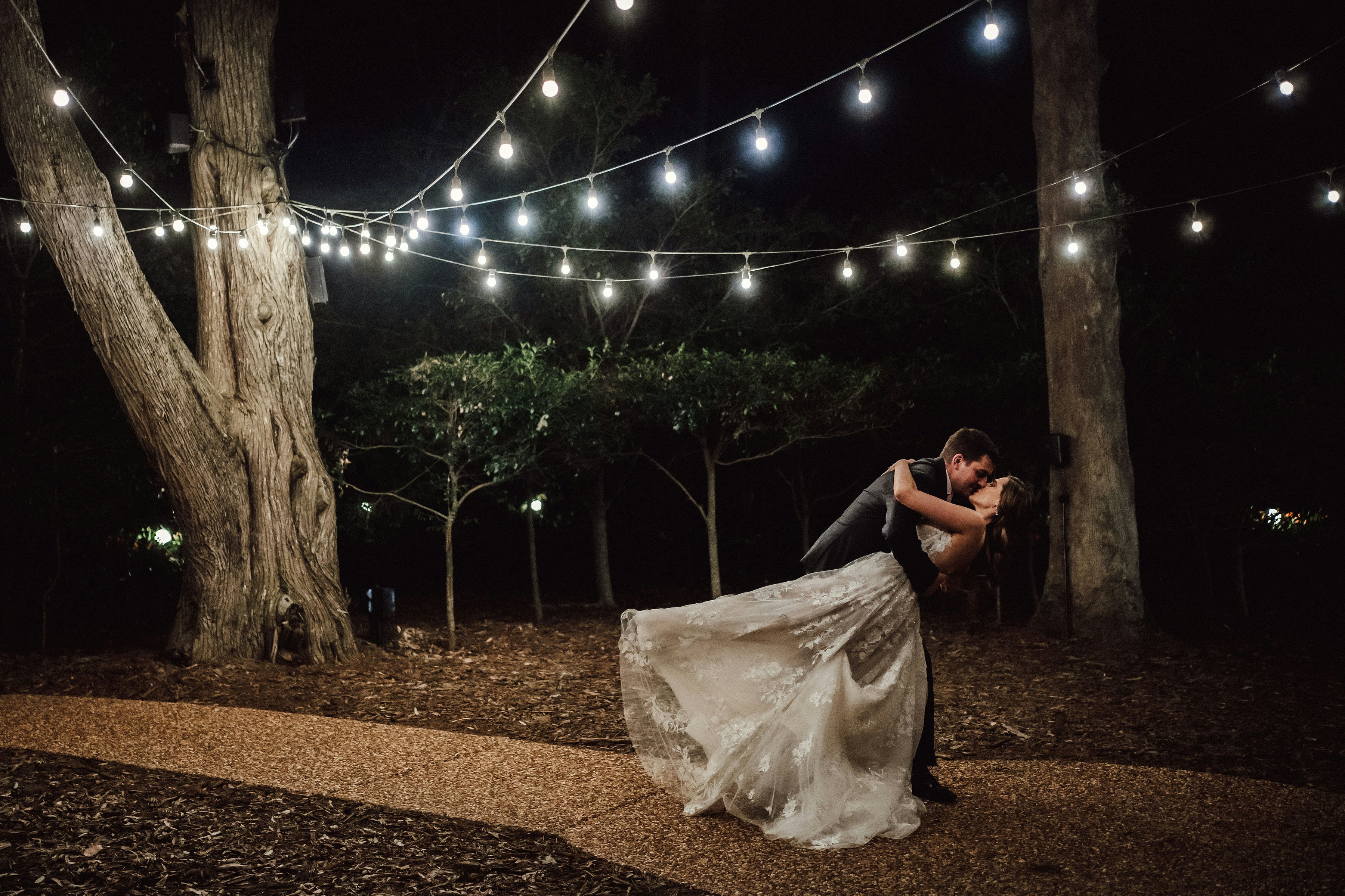Bride and groom dancing under festoon lights
