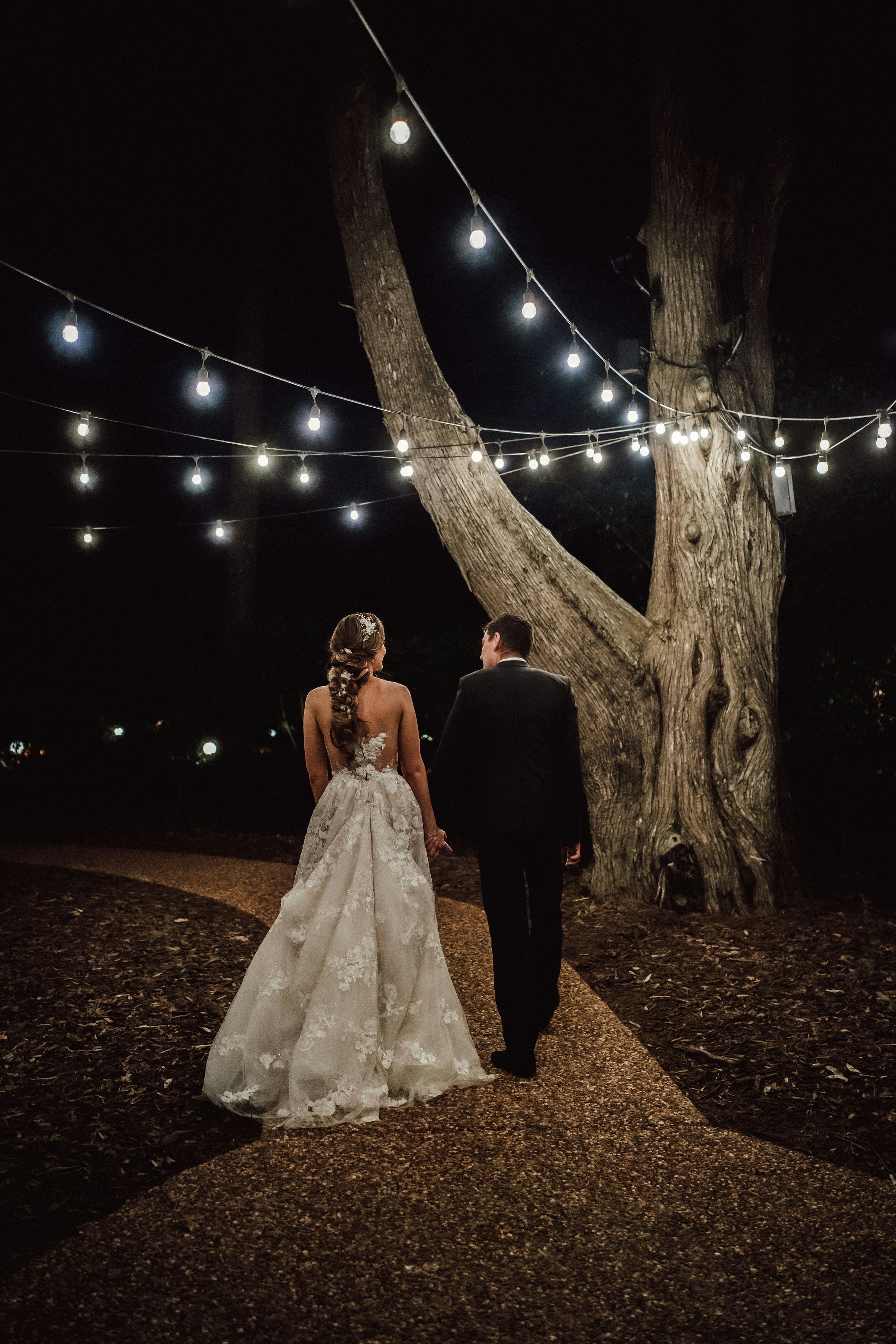 Bride and groom dancing under festoon lights 