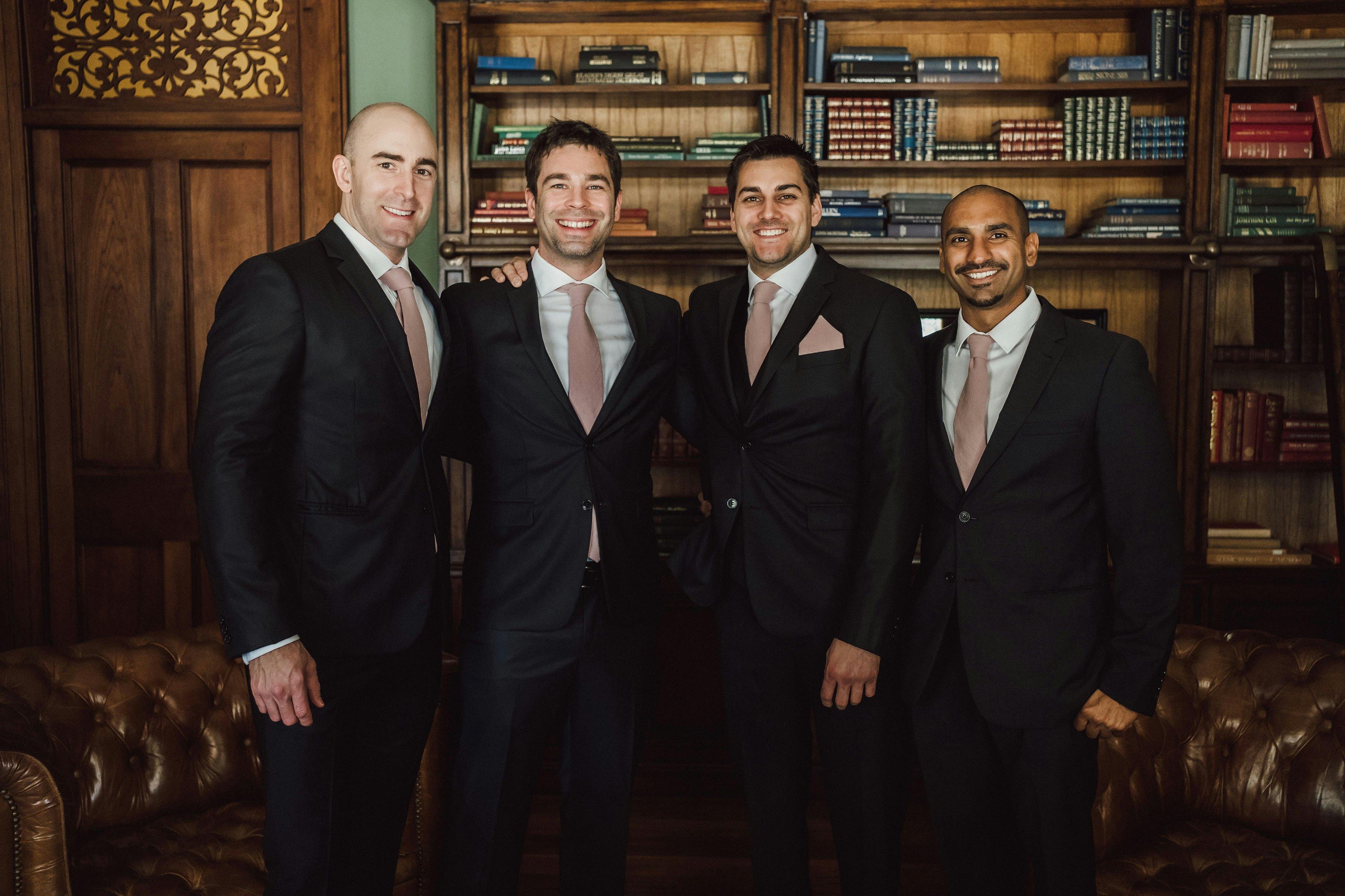 Groom and groomsmen standing in library together 