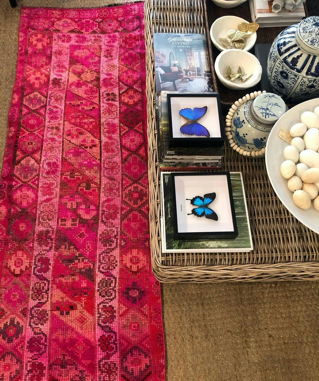 Pink turkish rug next to rattan coffee table with pots on it
