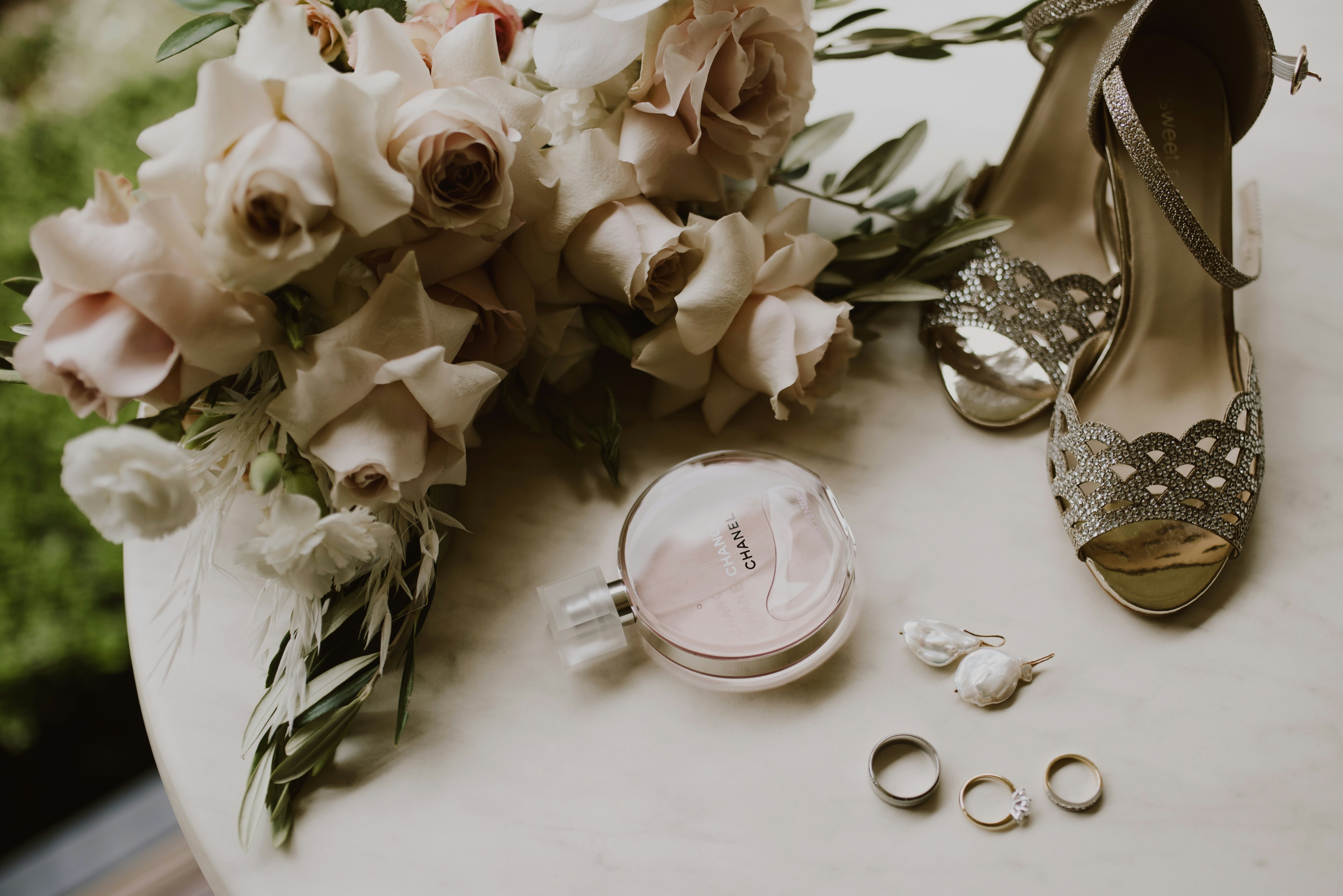 Shoes, perfume, wedding rings, bouquet arranged on a table 
