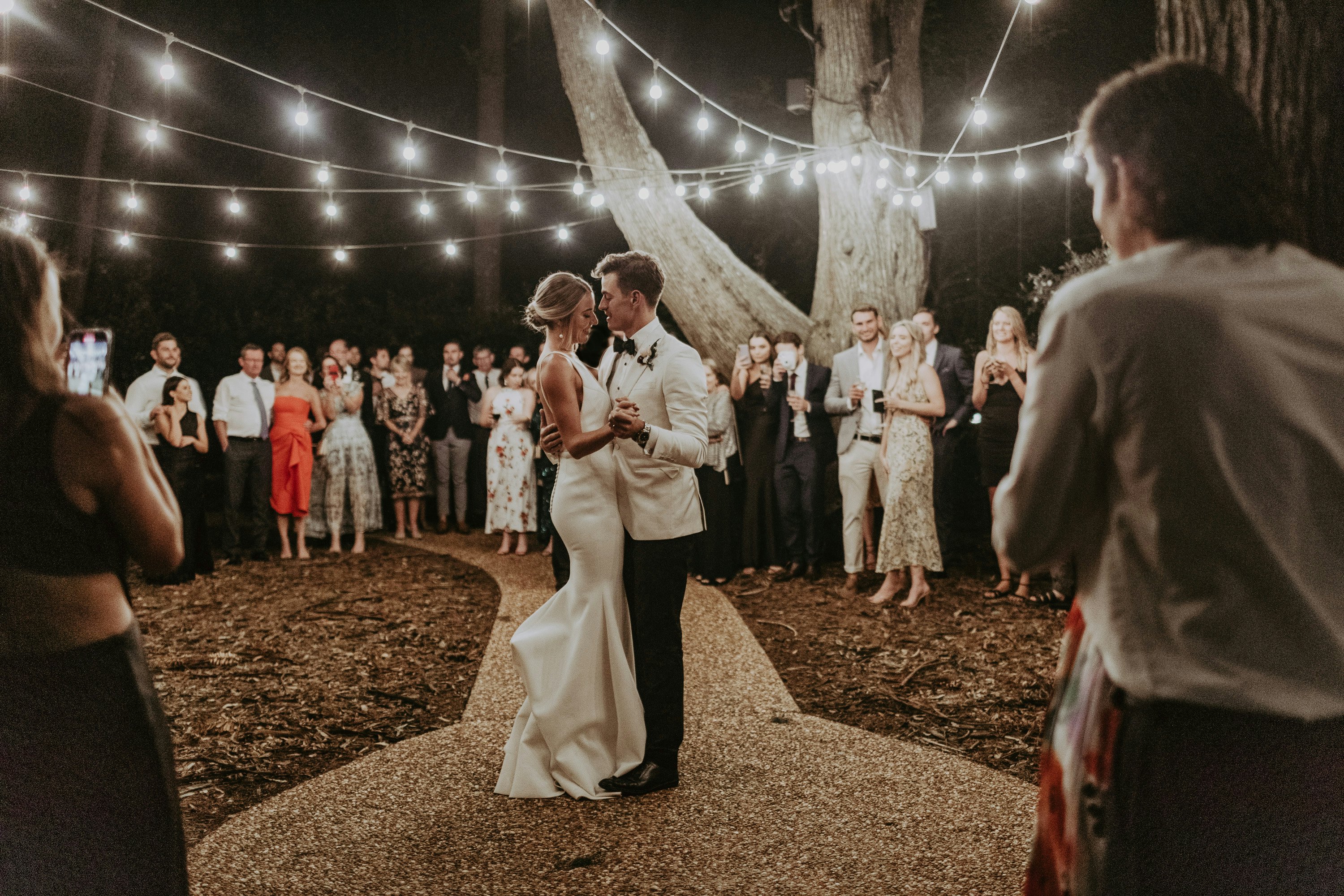 Bride and groom dancing under festoon lights 