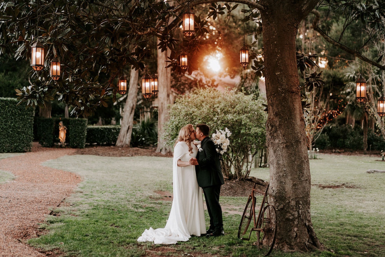Bride and groom kissing under tree 
