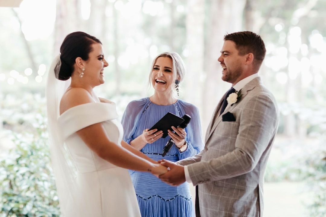 Bride and groom laughing with celebrant