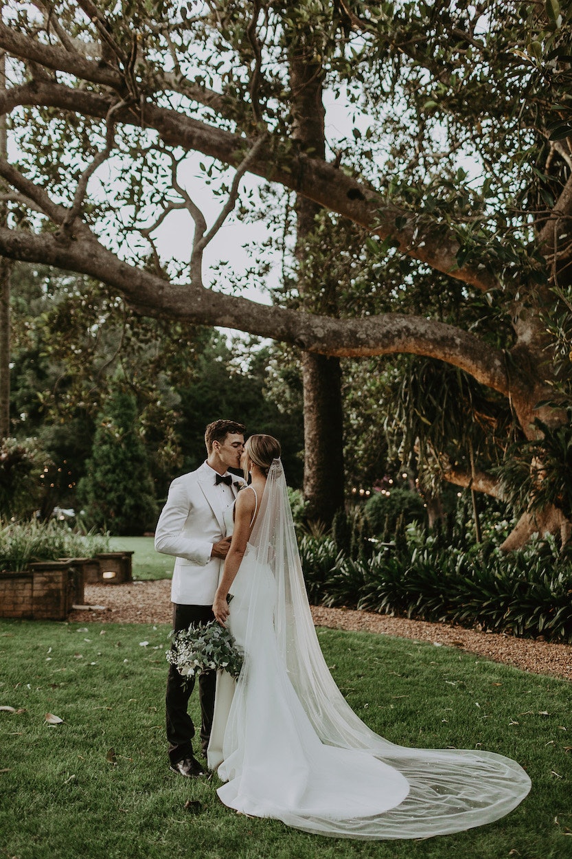 Bride and groom standing under tree 