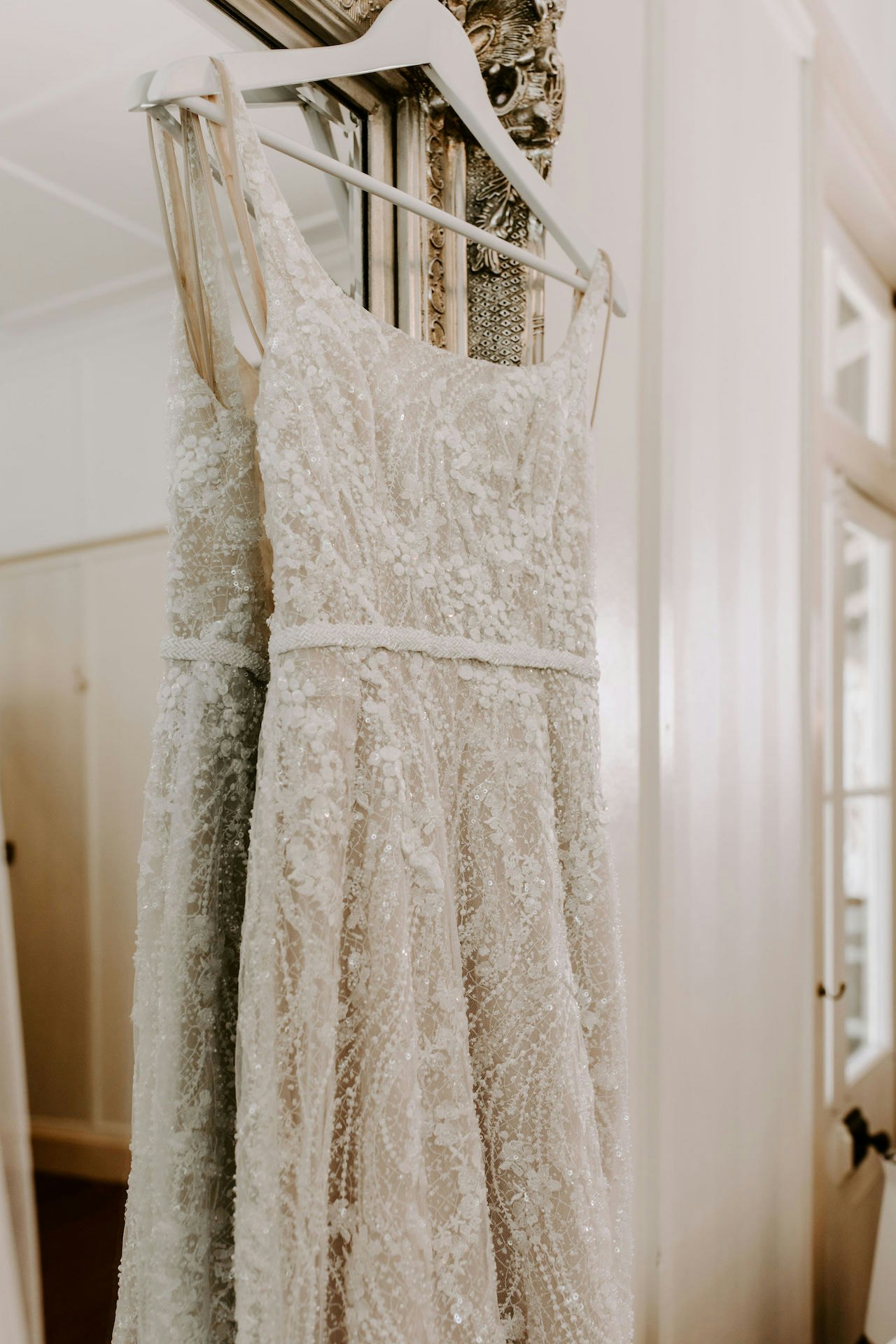 Wedding dress hanging in front of mirror 