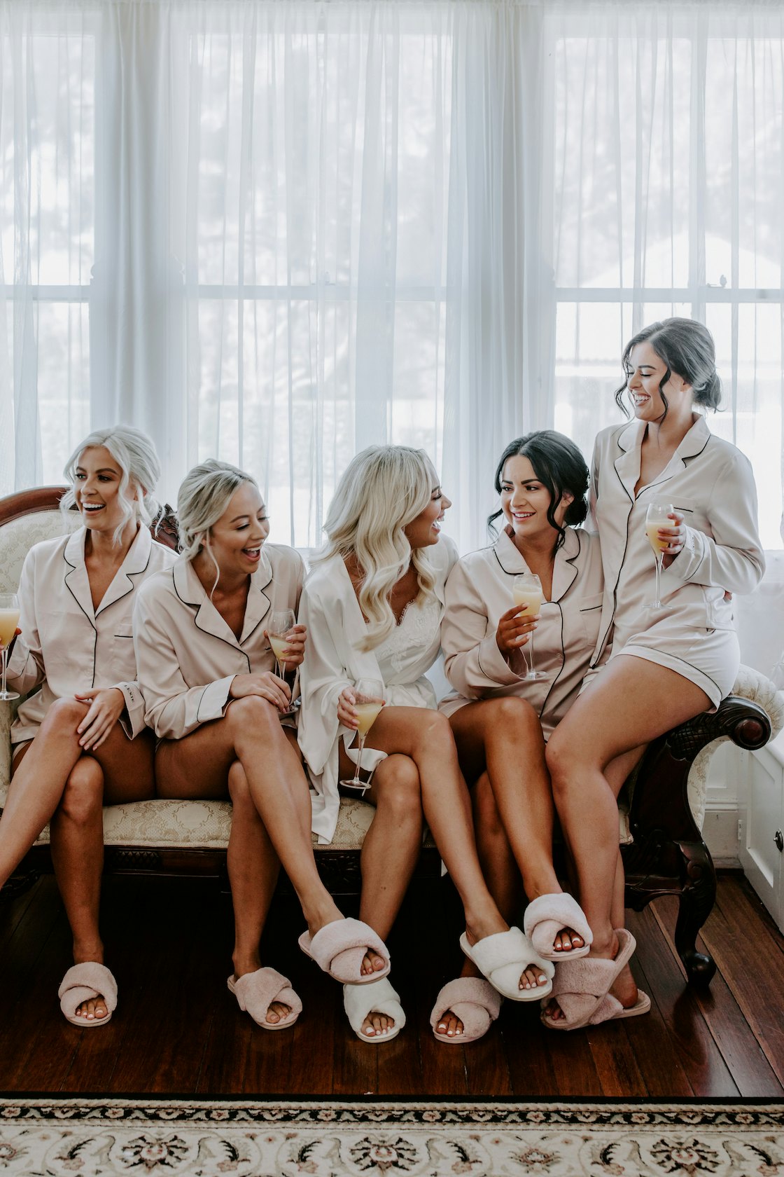 Bride sitting on lounge with bridesmaids 