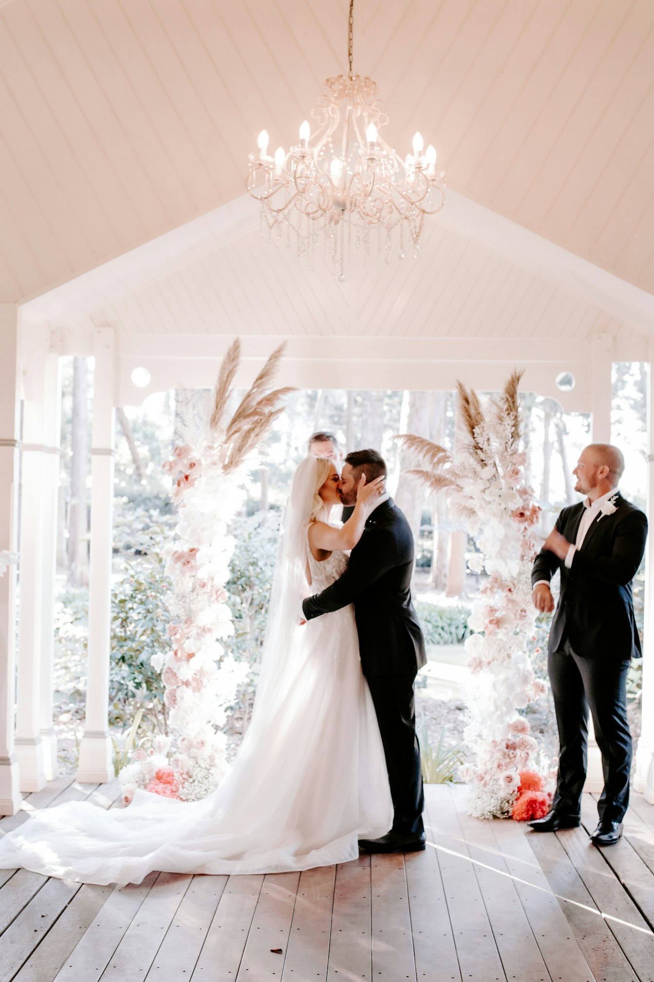 Bride and groom kissing under arbor 