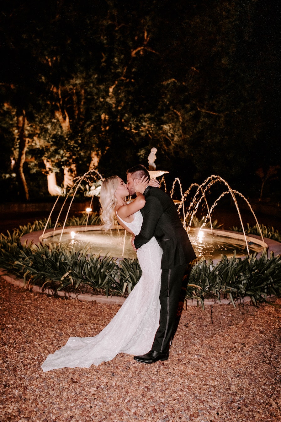 Bride and groom kissing in front of fountain 