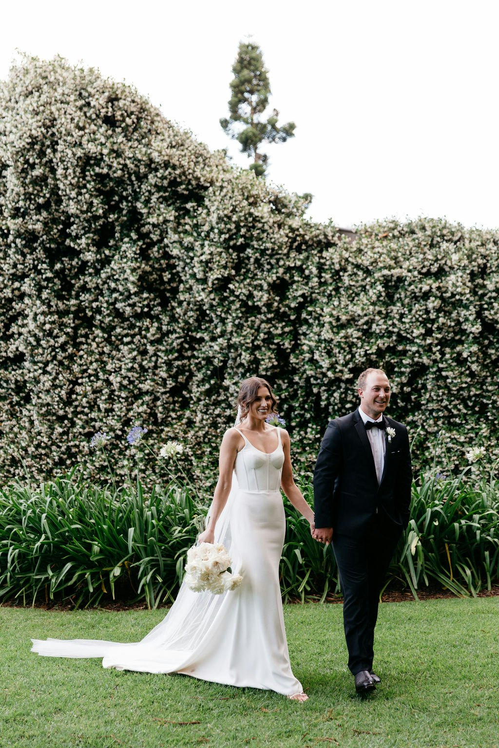Bride and groom walking through gardens 