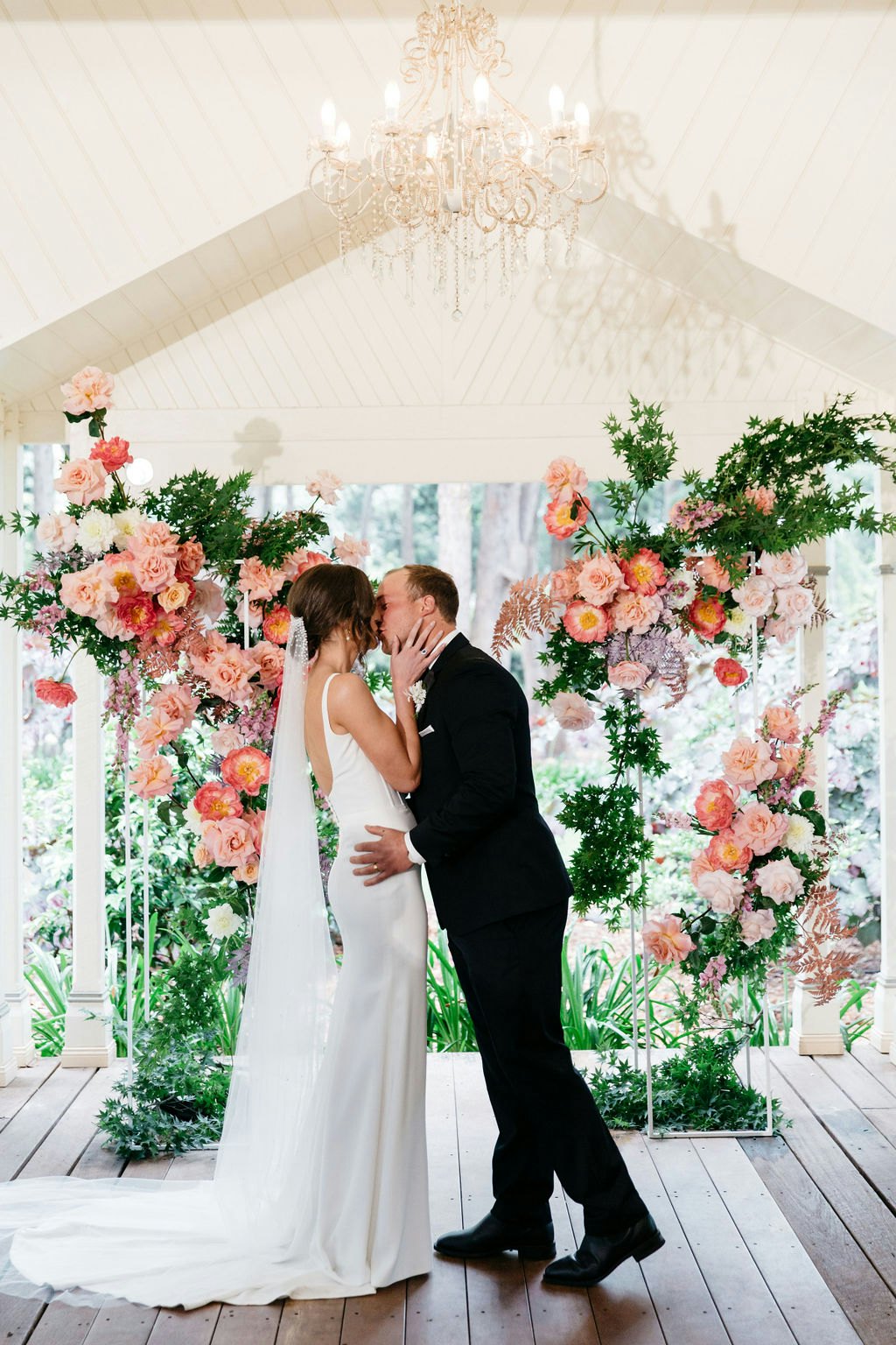 Bride and groom kissing in front of arbour 