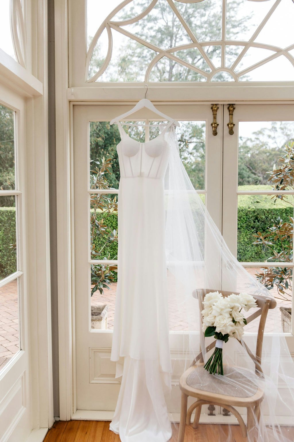 Wedding dress hanging in front of window 