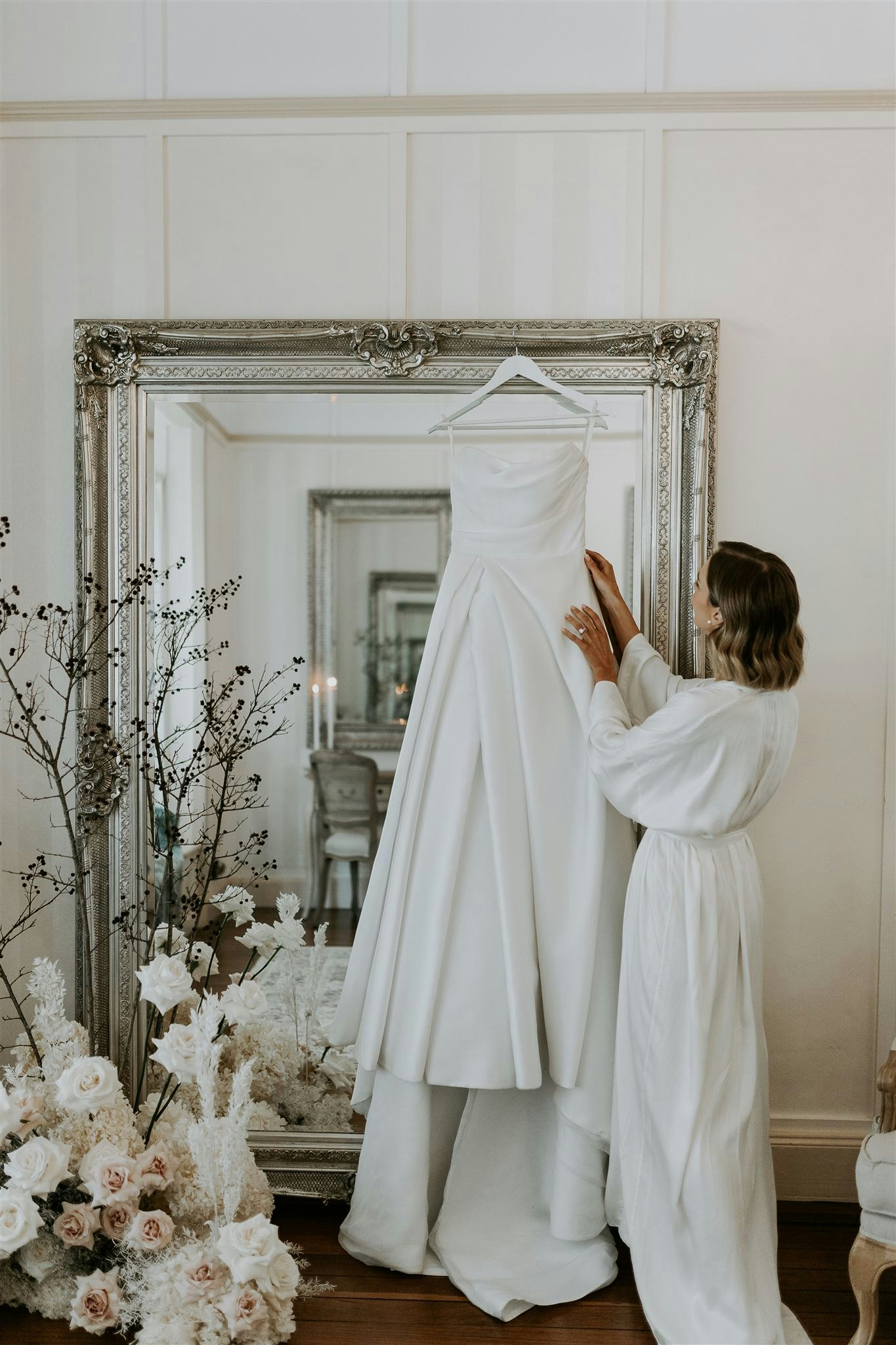 Bride prepares on wedding day by reaching up and touching her gown