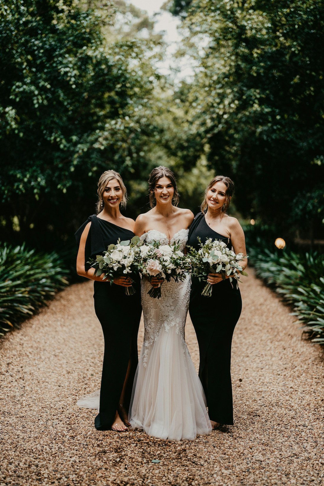 Bride standing in driveway with bridesmaids