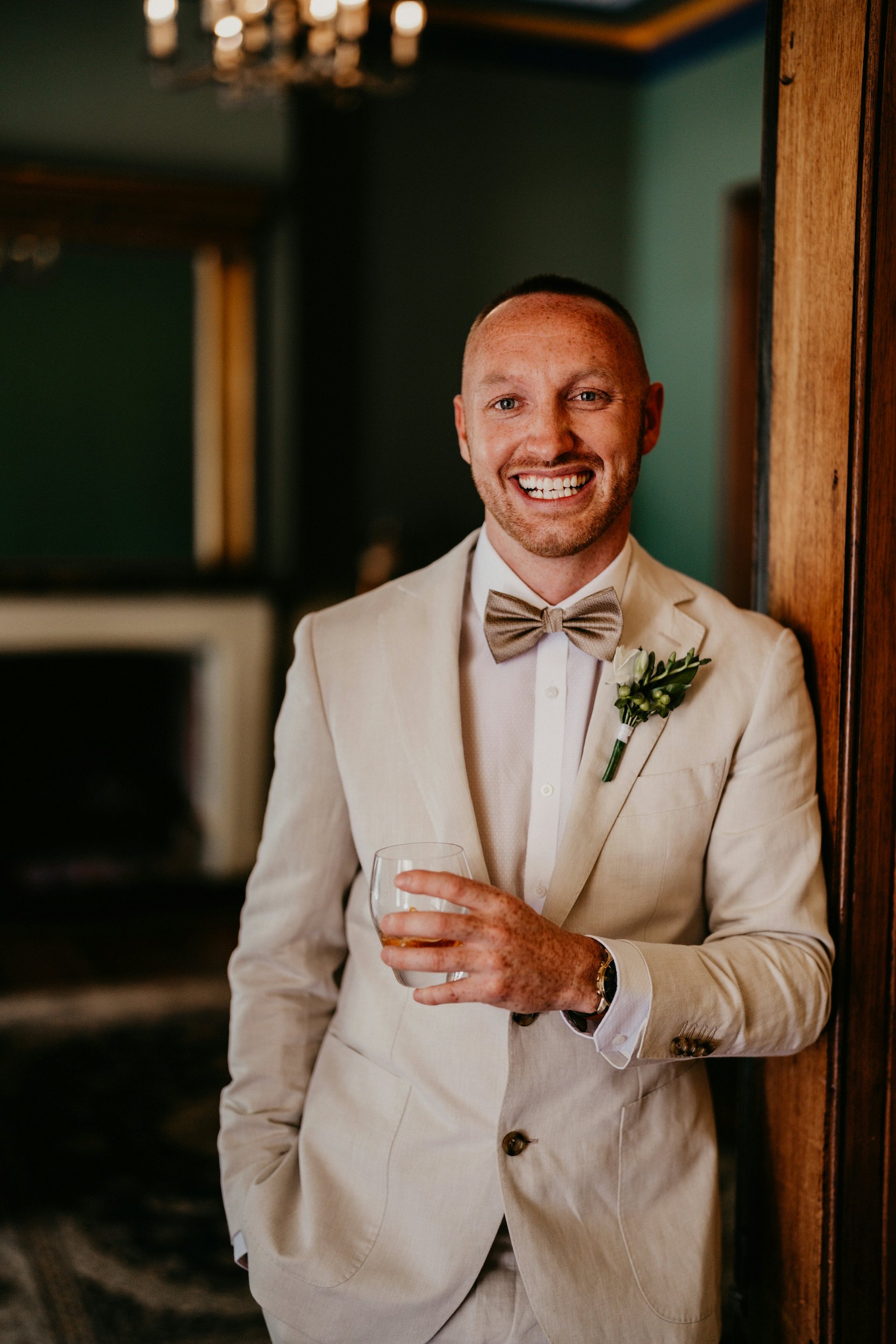 Groom holding drink in library