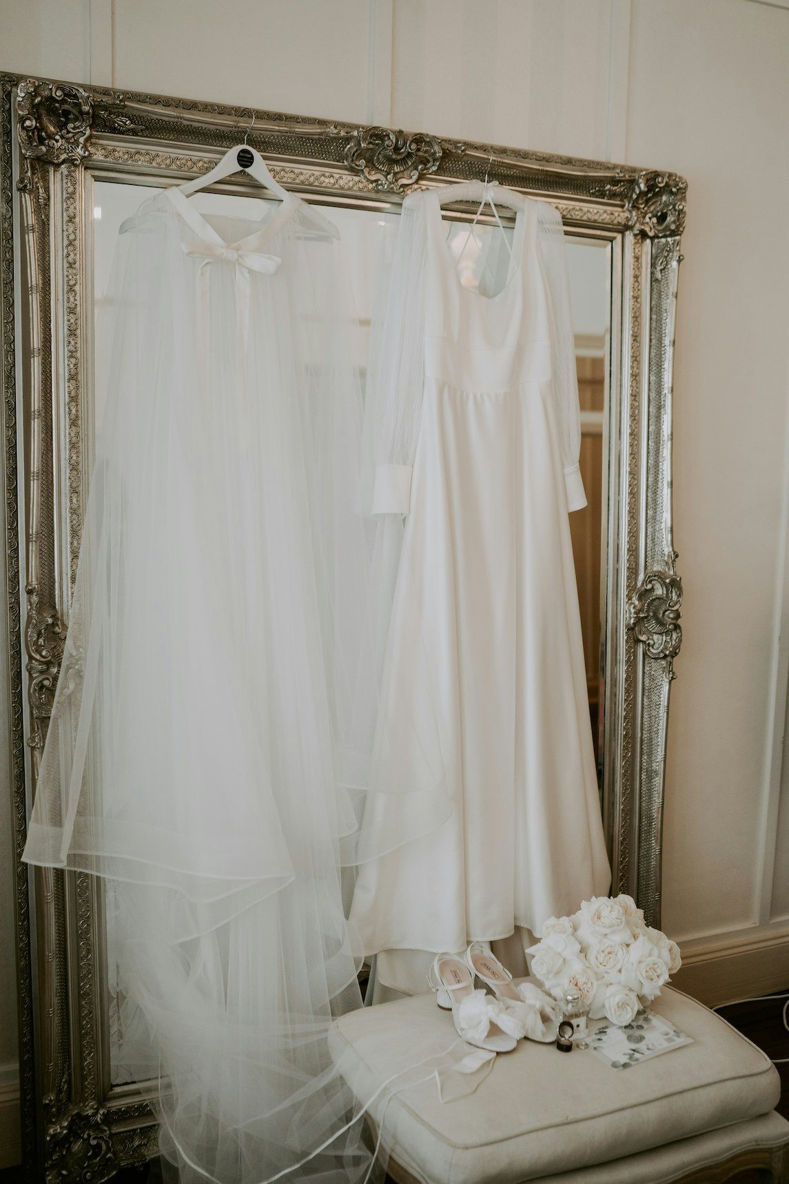 Wedding dress, shoes and veil hanging on mirror