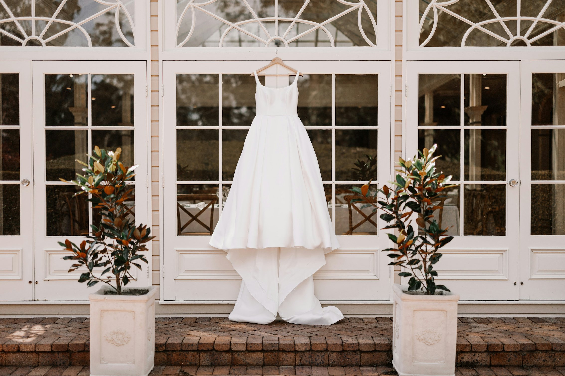 Wedding dress hanging in front of french doors