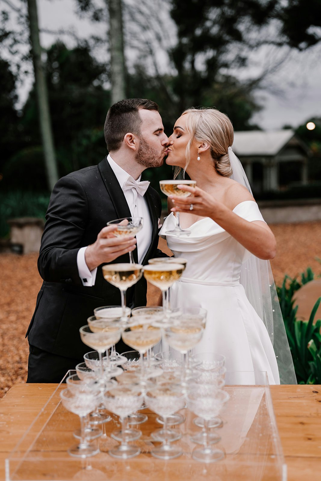 Bride and groom kissing behind champagne tower