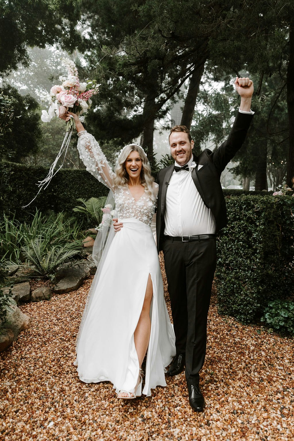 Bride and groom celebrating holding bouquet in the air