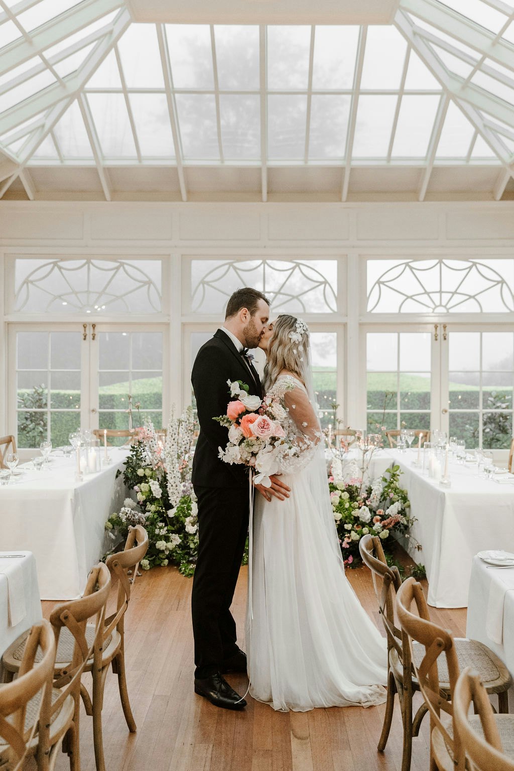 Bride and groom kissing in conservatory