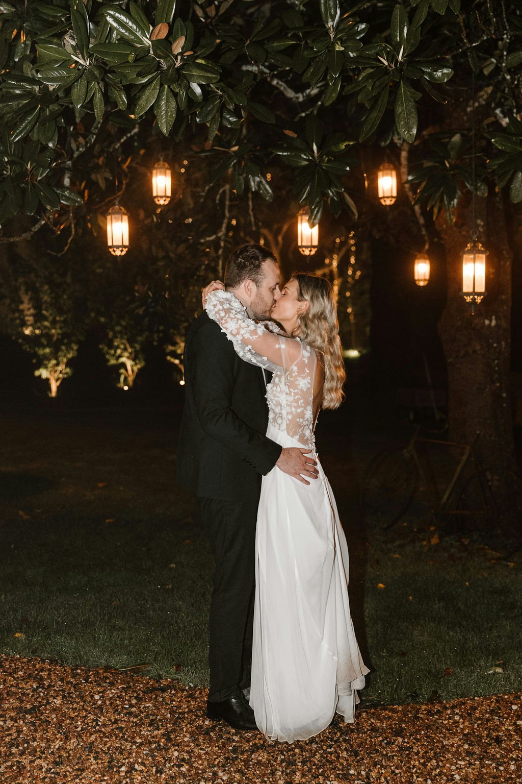 Bride and groom kissing under lanterns in tree outside