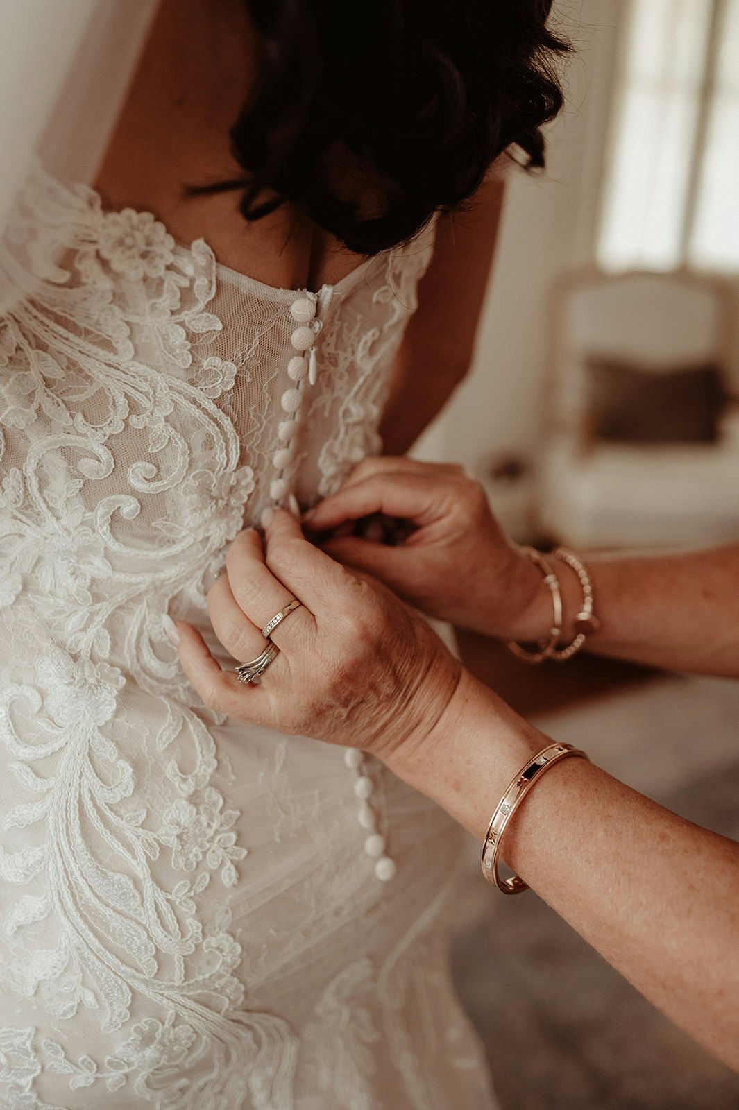 Mother of bride doing wedding dress buttons up