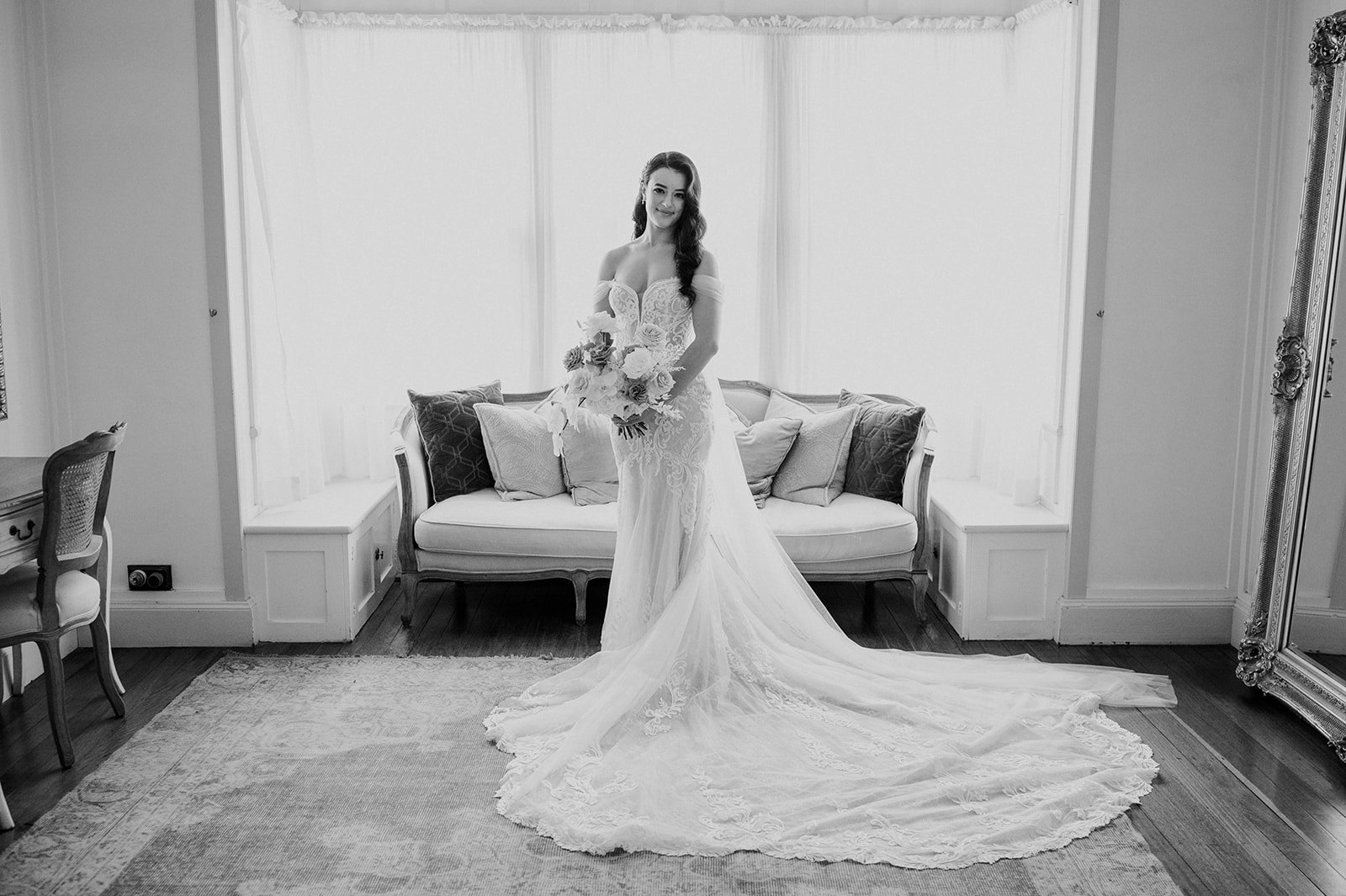 Bride standing in wedding dress in front of couch