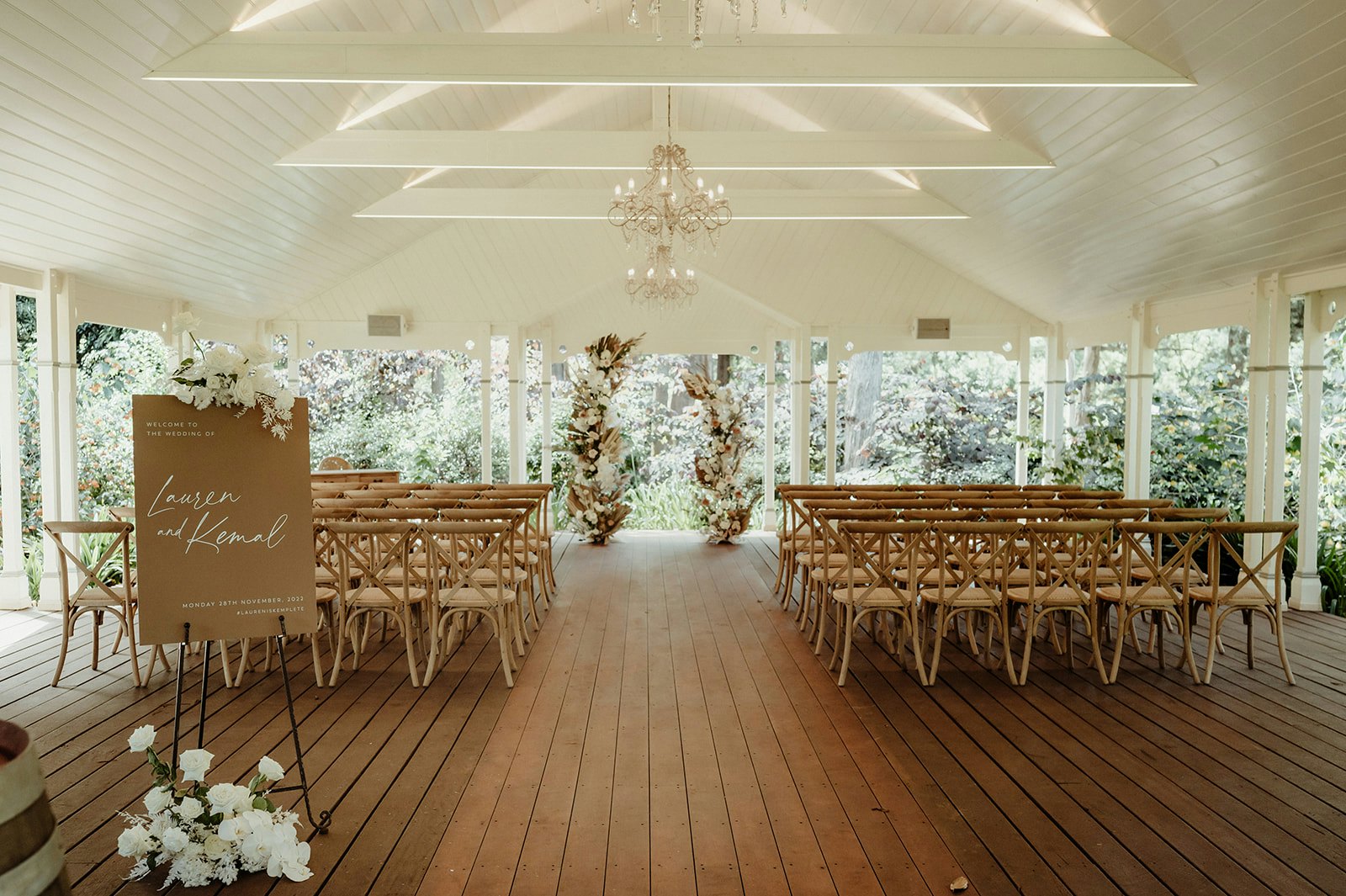 Wedding ceremony with wooden chairs and floral arbour