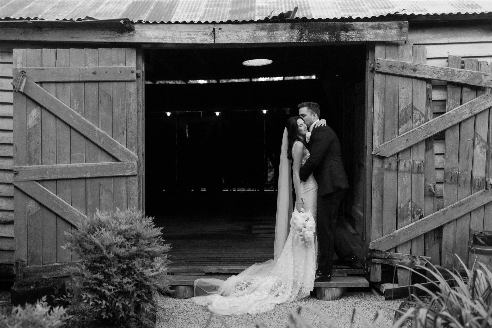 Bride and groom standing in wooden stables