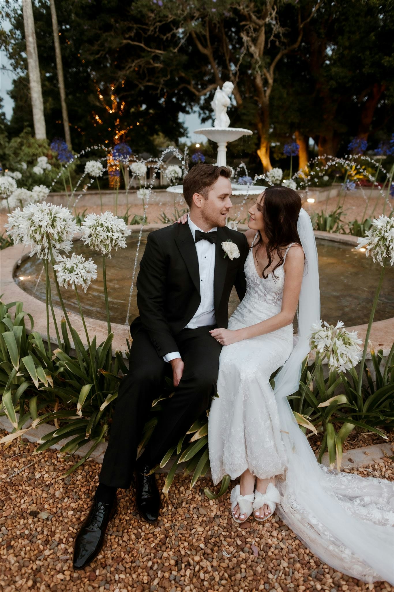Bride and groom sitting by fountain
