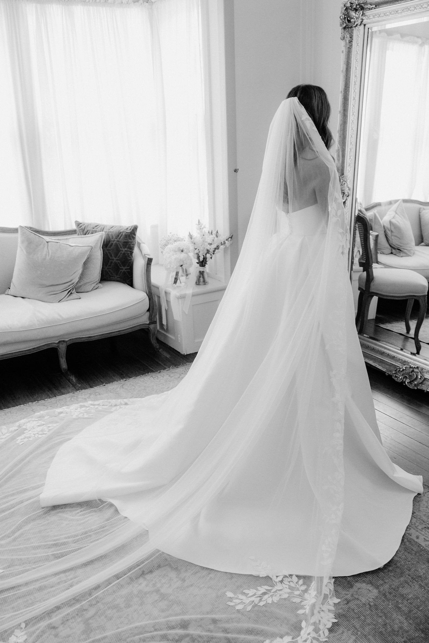 Bride standing in front of mirror with wedding dress and veil