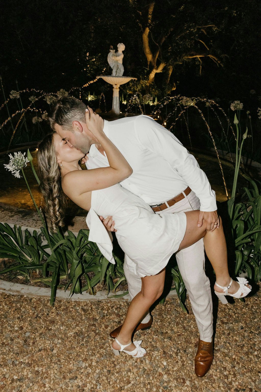 Bride and groom kissing in front of fountain