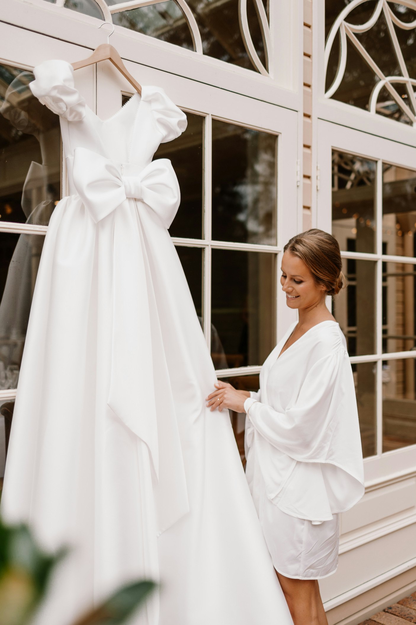 Bride looking at hanging wedding dress