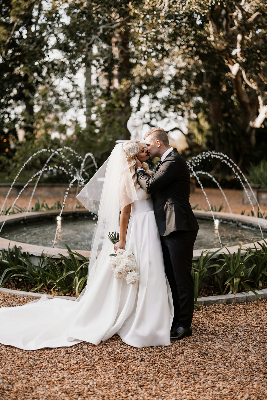 Bride and groom kissing in front of fountain