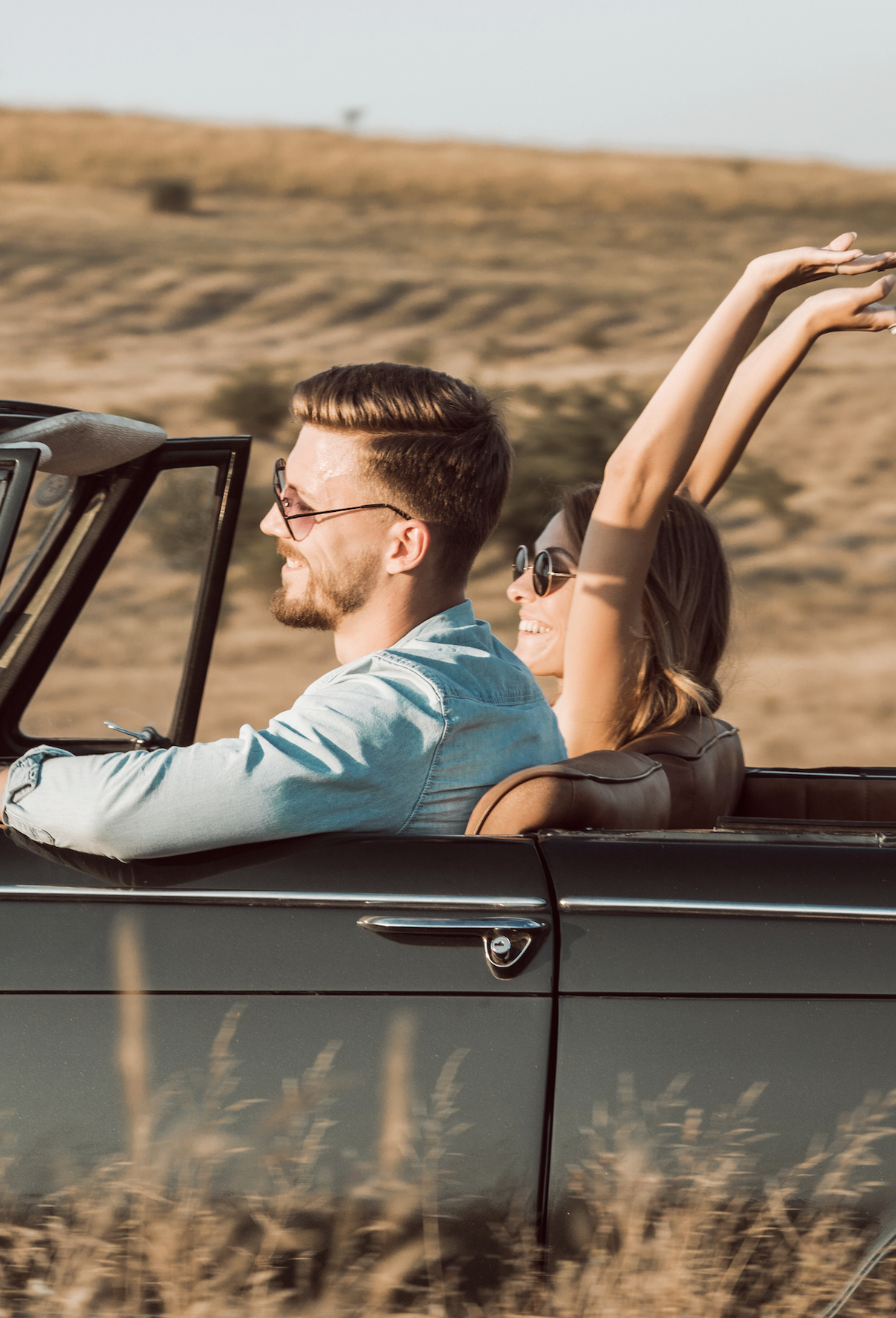 Couple drive with girls arms in air