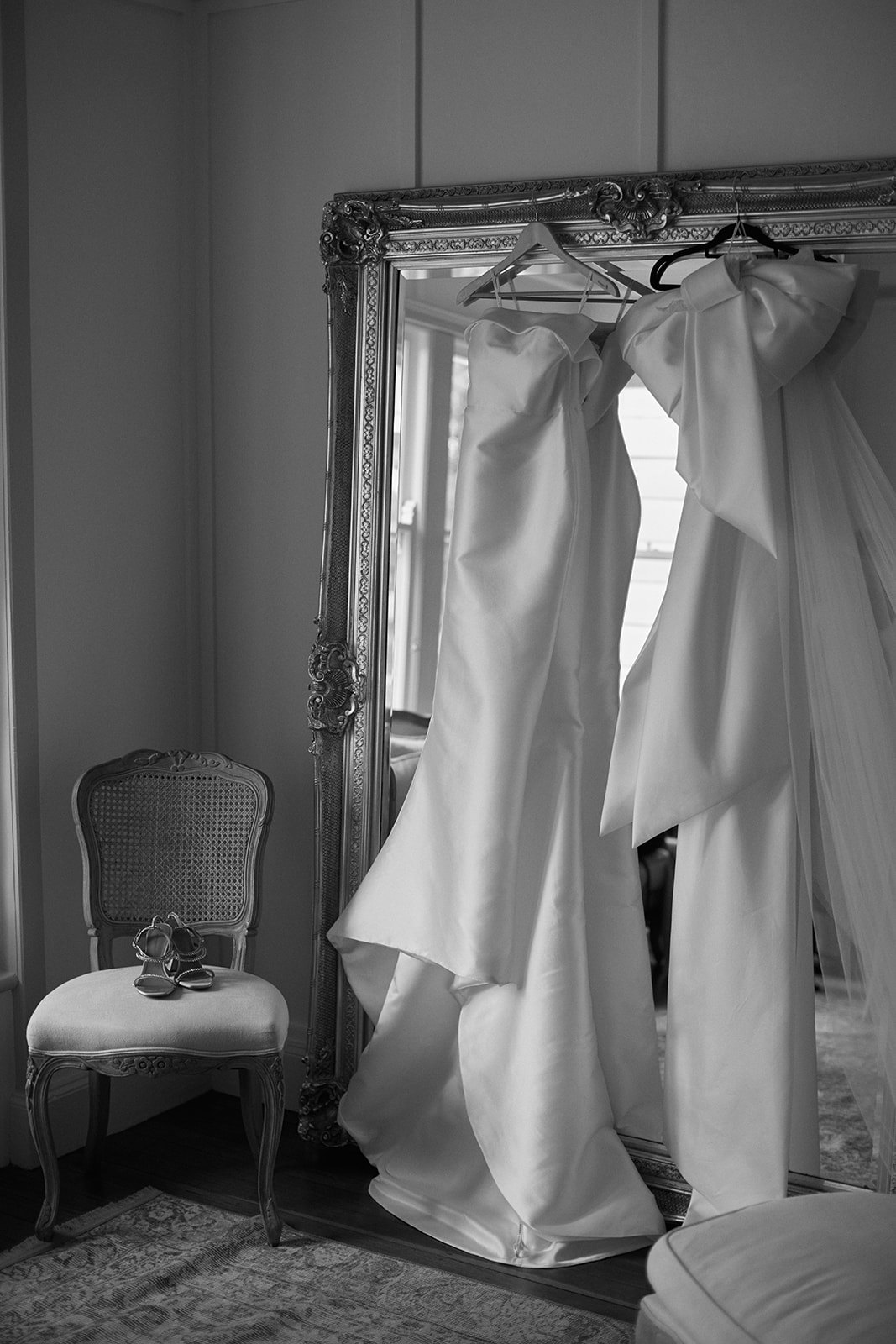 Brides wedding dress hanging in front of mirror