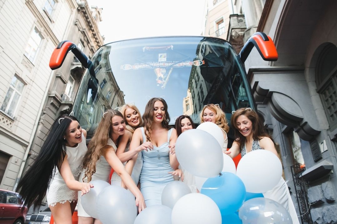 Women holding balloons in front of bus