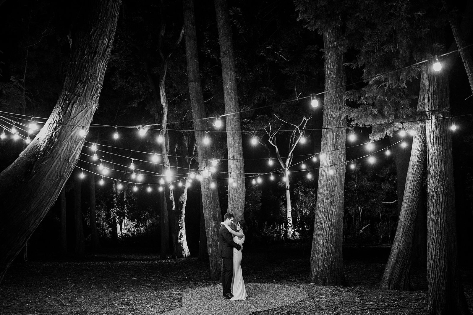 Bride and groom under festoon lights