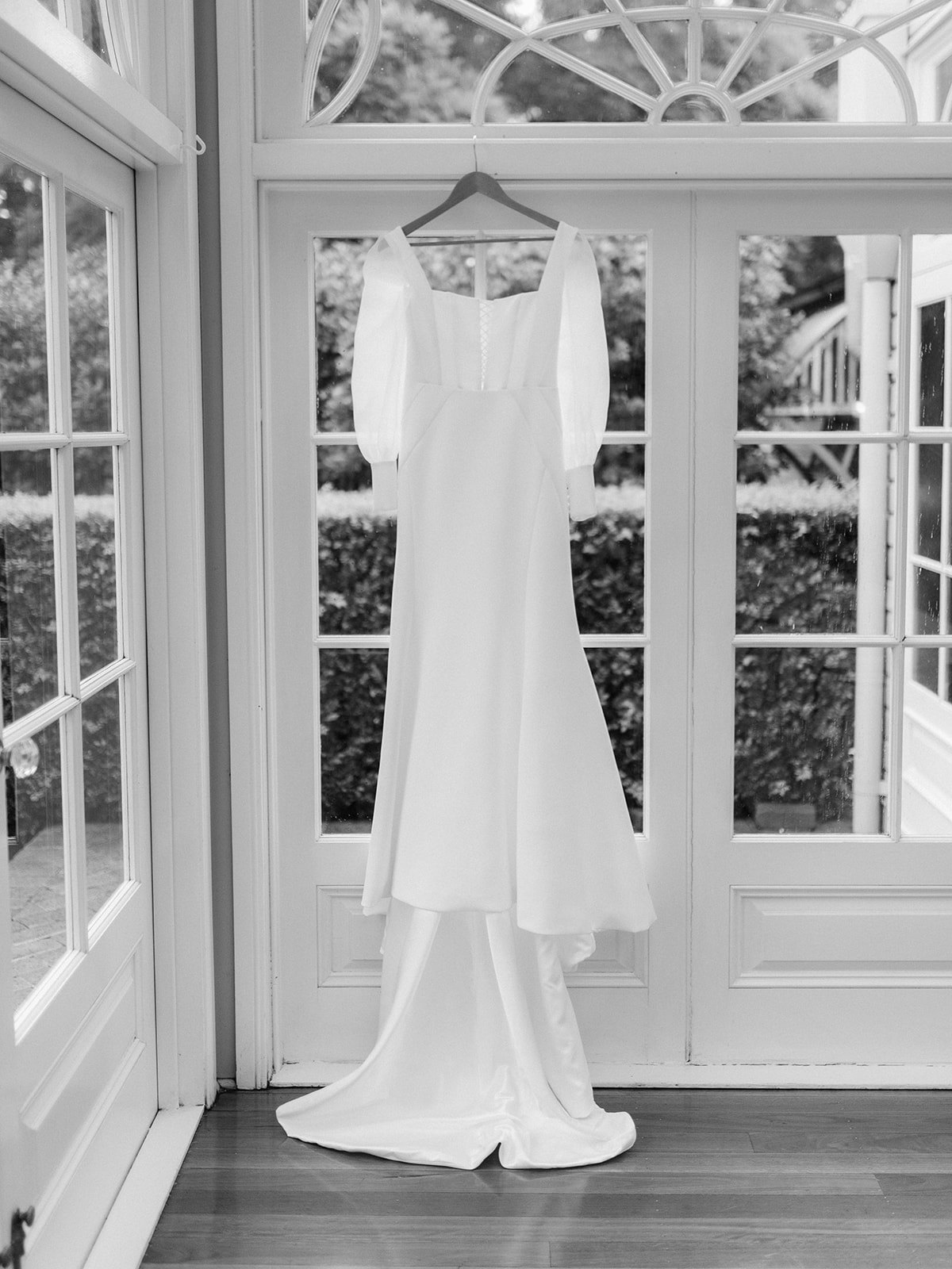 Wedding dress hanging in front of french doors