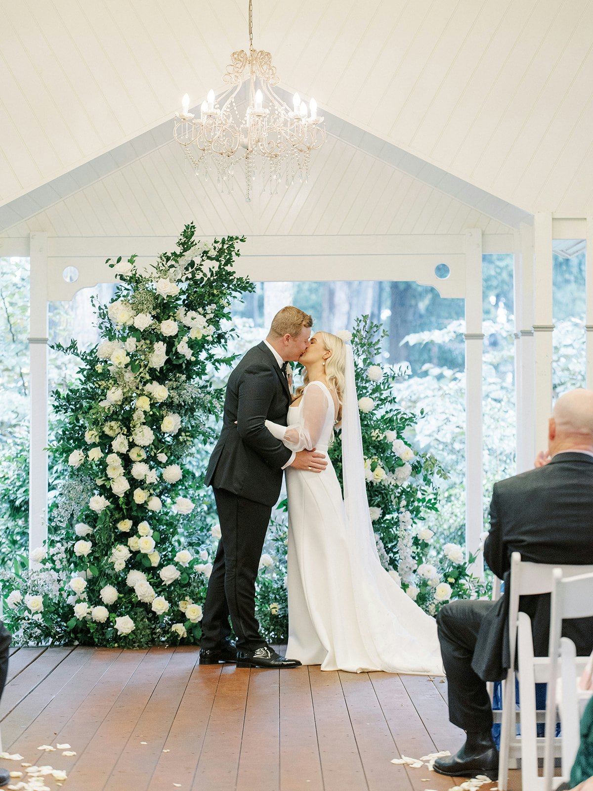 Bride and groom kissing in front of arbour