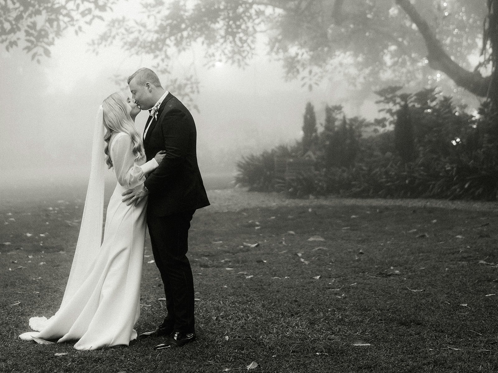 Bride and groom kissing in the fog