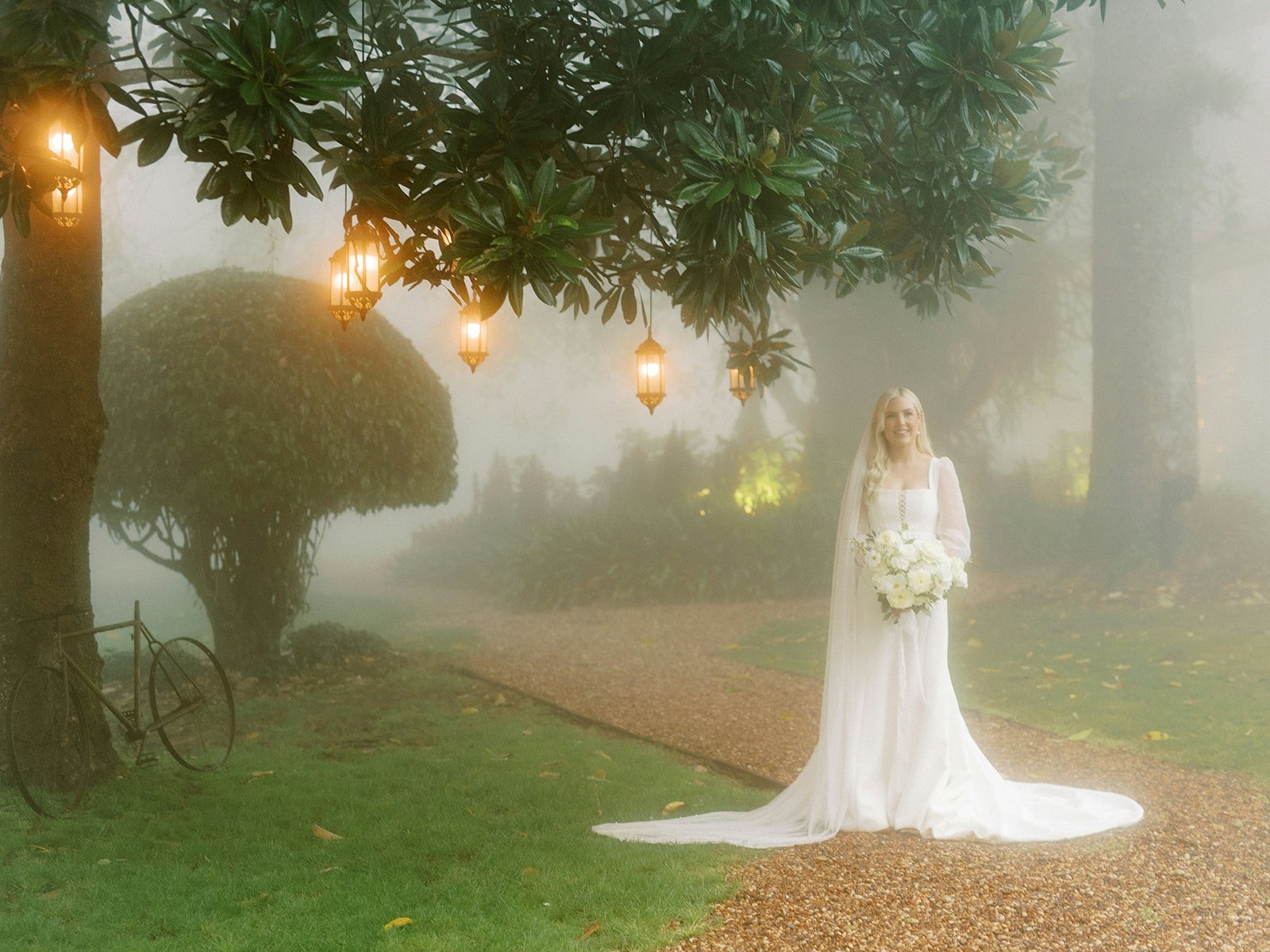 Bride standing under tree with lanterns