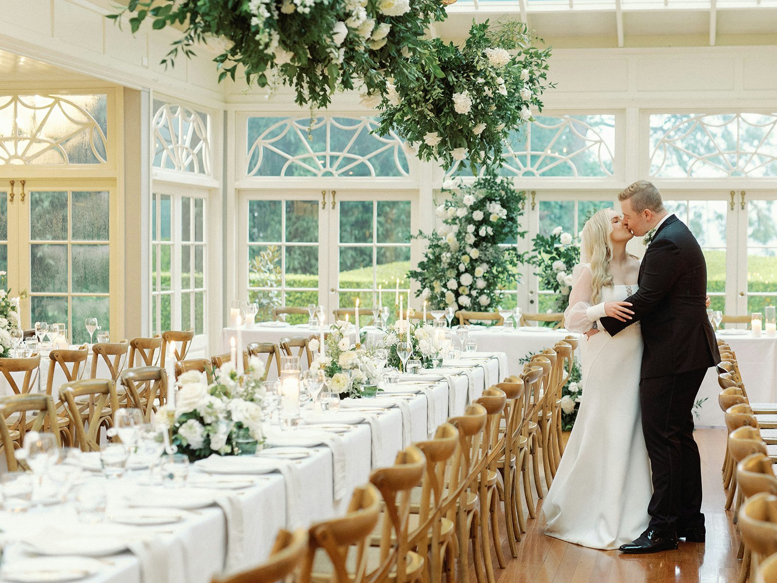 Bride and groom kissing under hanging flowers