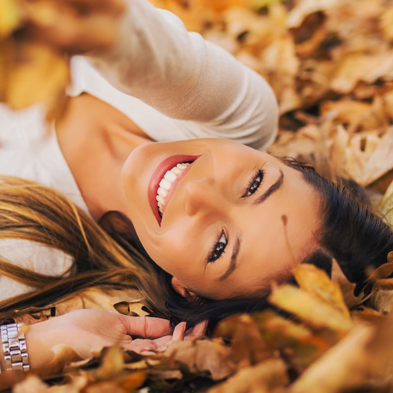 Smiling woman lying in the leaves